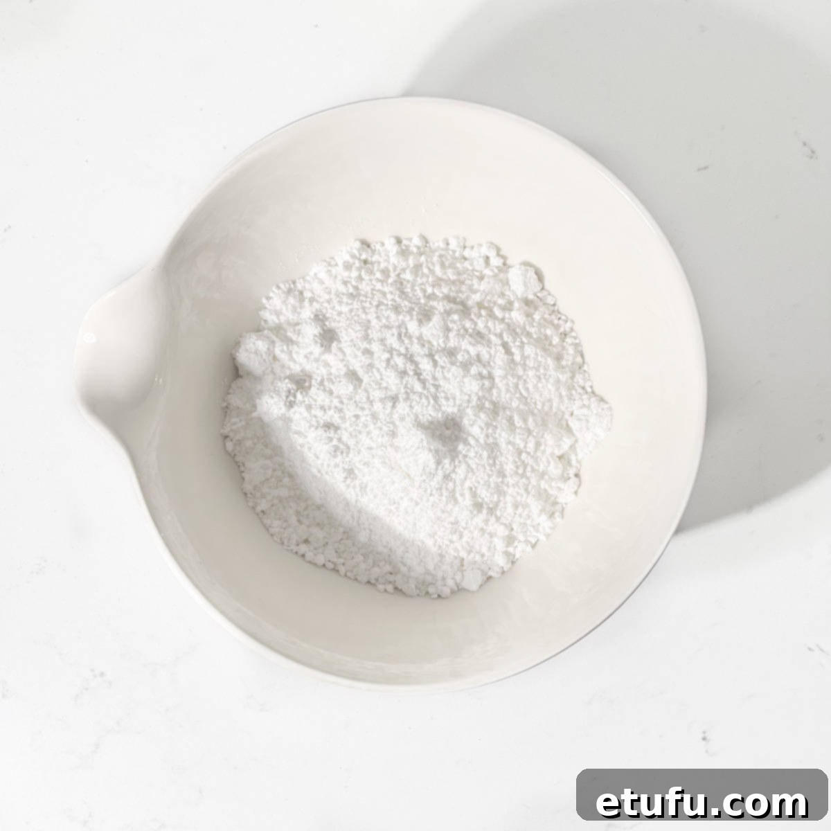 Icing sugar in a white bowl for the Christmas cookies with edible wafer paper. Powdered sugar ready for mixing.