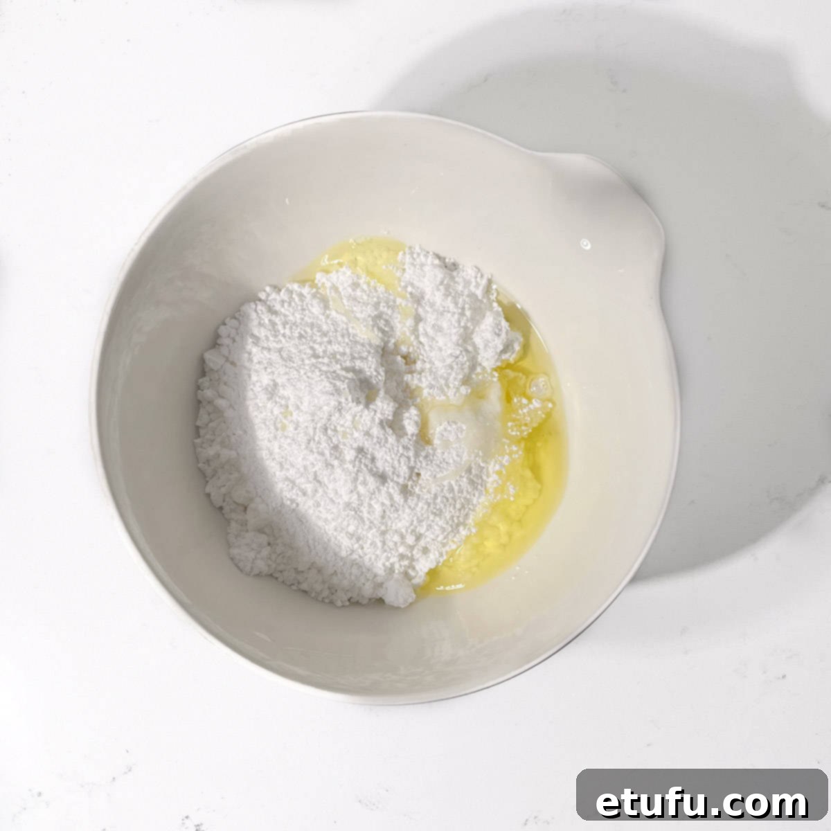 Adding the egg white to the icing sugar in a bowl.