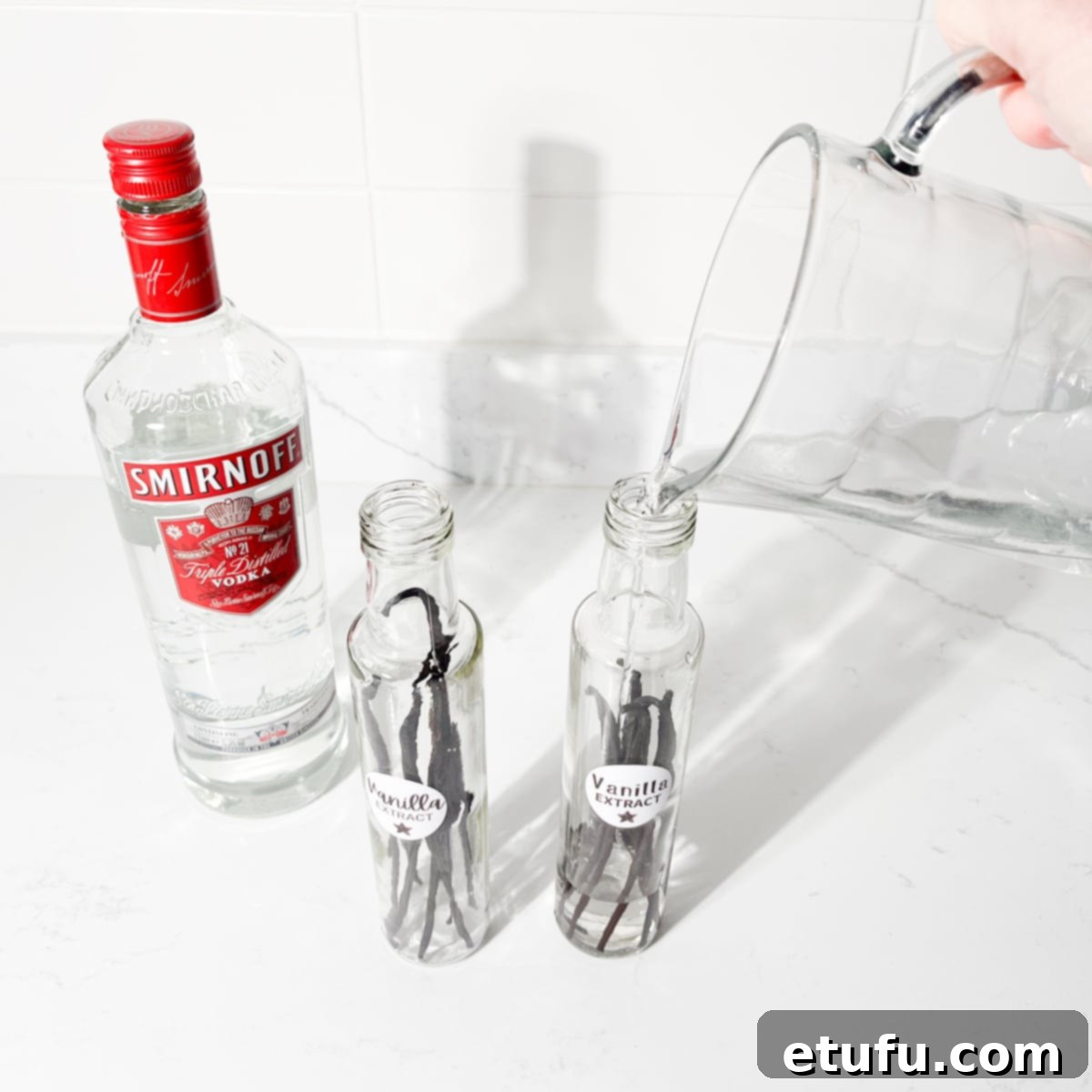Adding vodka to the glass bottle to make homemade vanilla extract.