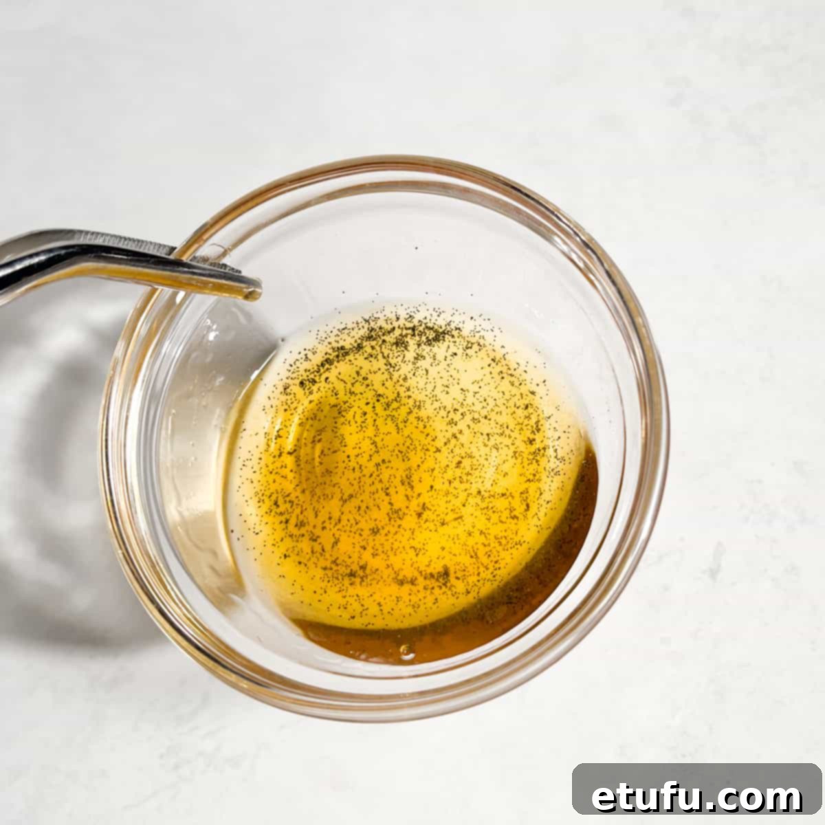 Vanilla extract in a glass bowl showing the amount of seeds in it against the light.