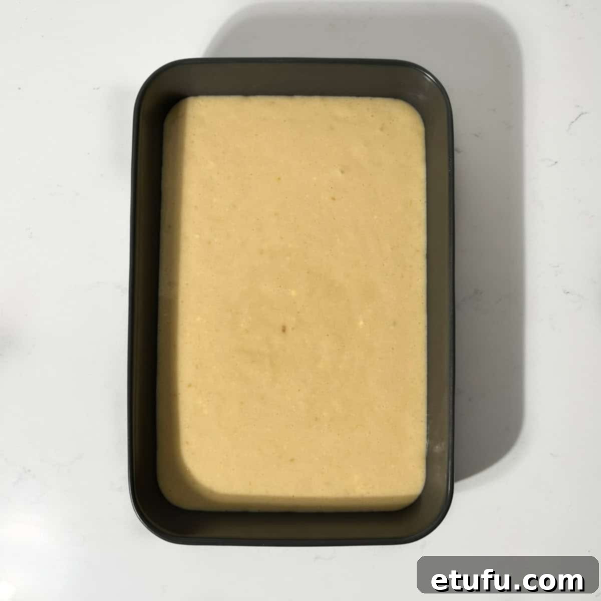 Sticky South African Malva Delight 11 Pudding batter in a black baking dish, ready for the oven.