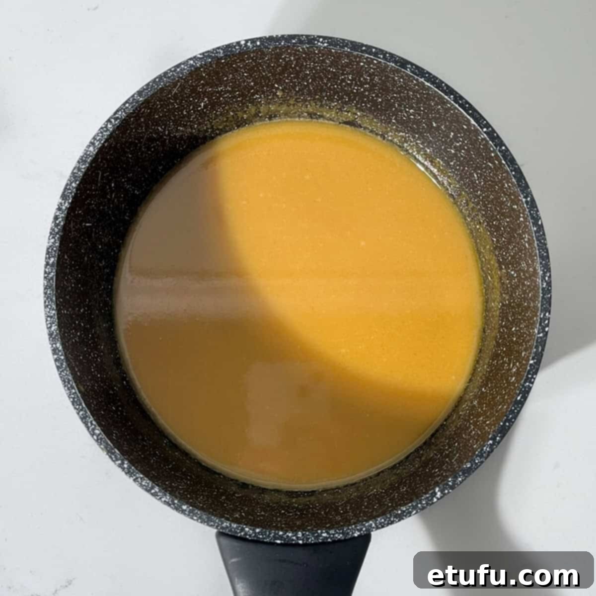 Sticky South African Malva Delight 13 Malva pudding cream sauce in a black saucepan.