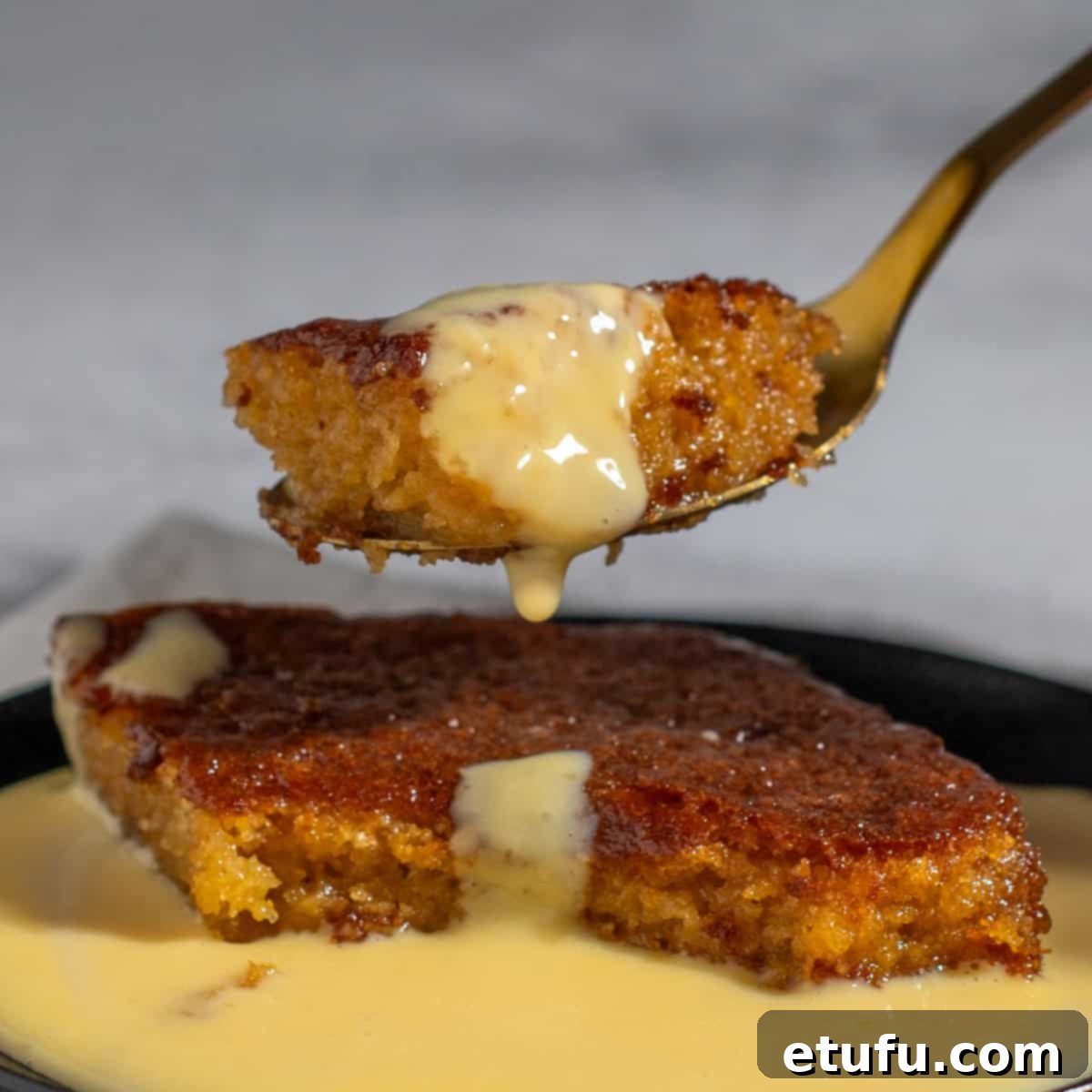 Sticky South African Malva Delight 16 A spoonful of malva pudding with custard dripping from it.