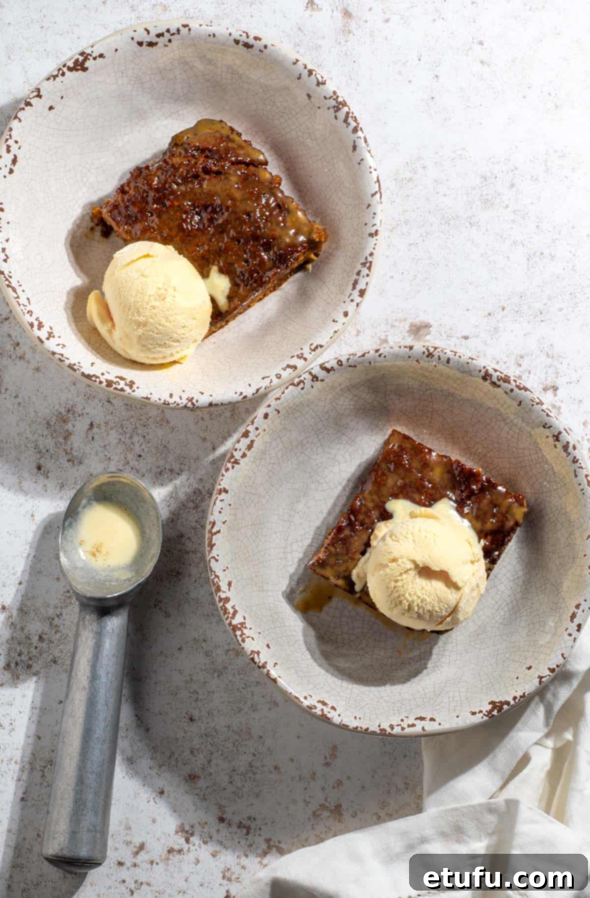 Sticky South African Malva Delight 17 Two bowls of malva pudding with scoops of ice cream on top.