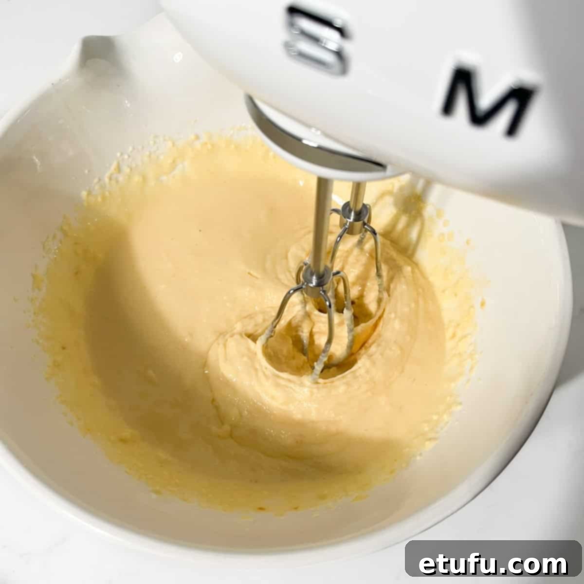 Sticky South African Malva Delight 7 Whisking the ingredients for the malva pudding in a large white bowl.