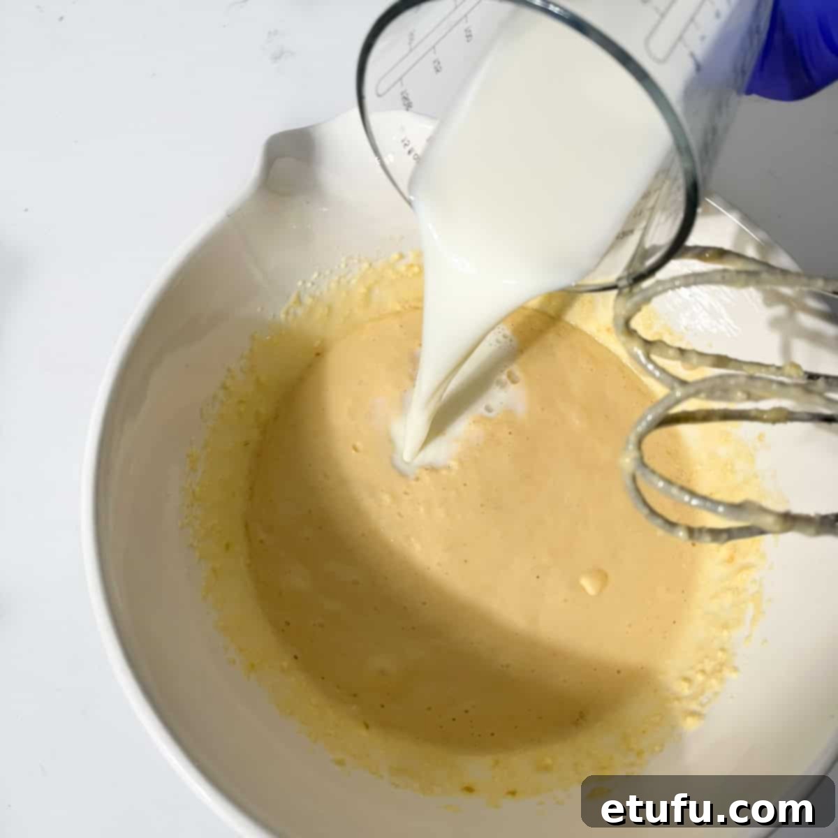 Sticky South African Malva Delight 8 Adding milk to the pudding batter in a large mixing bowl.