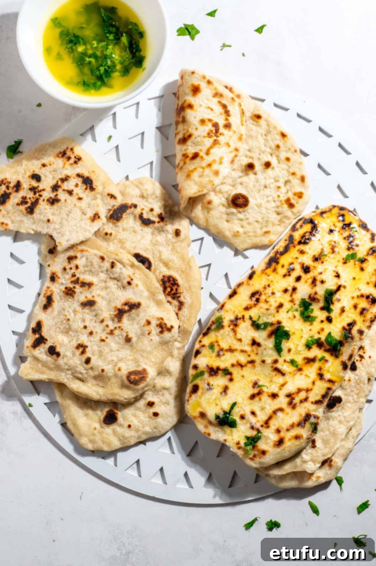 Two-ingredient flatbreads beautifully arranged on a white tray, accompanied by a small bowl of fresh parsley butter.