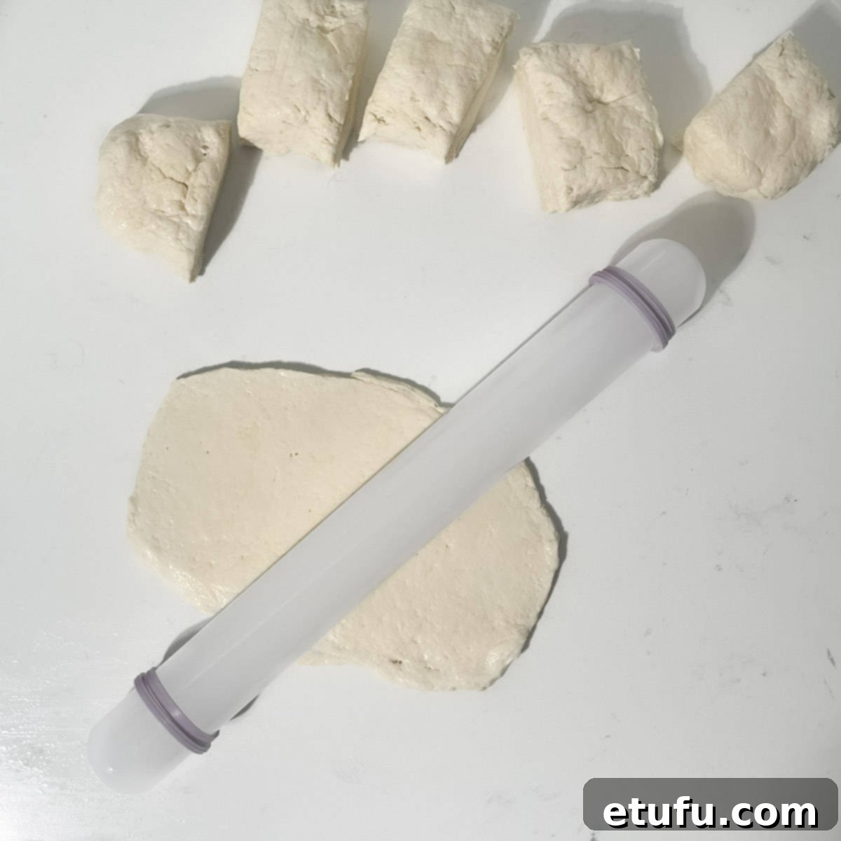 Rolling out a piece of 2-ingredient flatbread dough with a rolling pin on a floured surface.