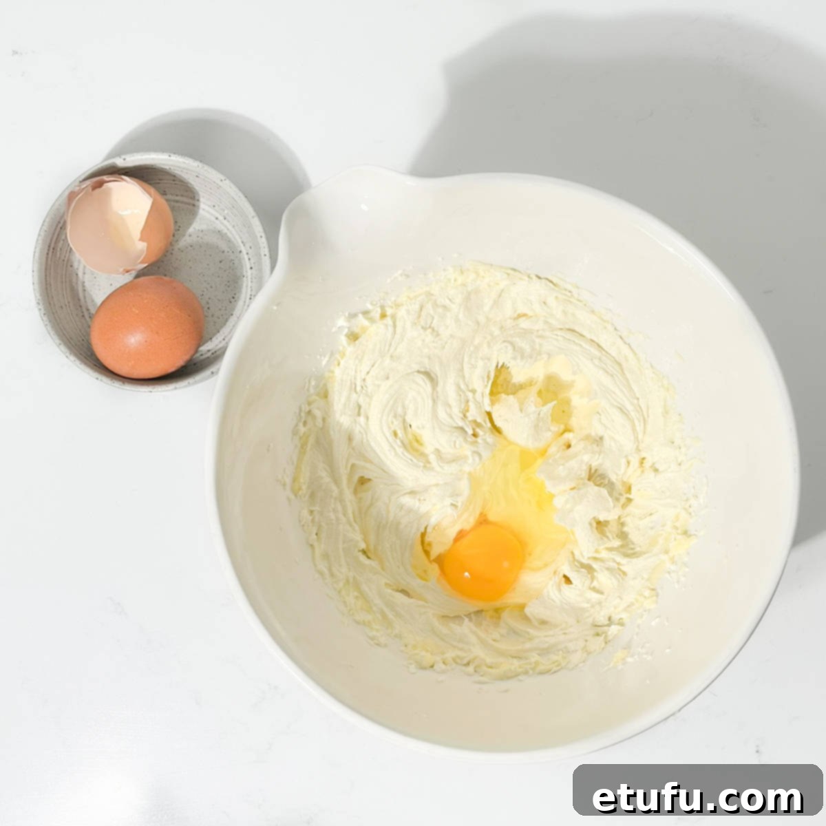 Add one egg to the batter in a large white bowl.