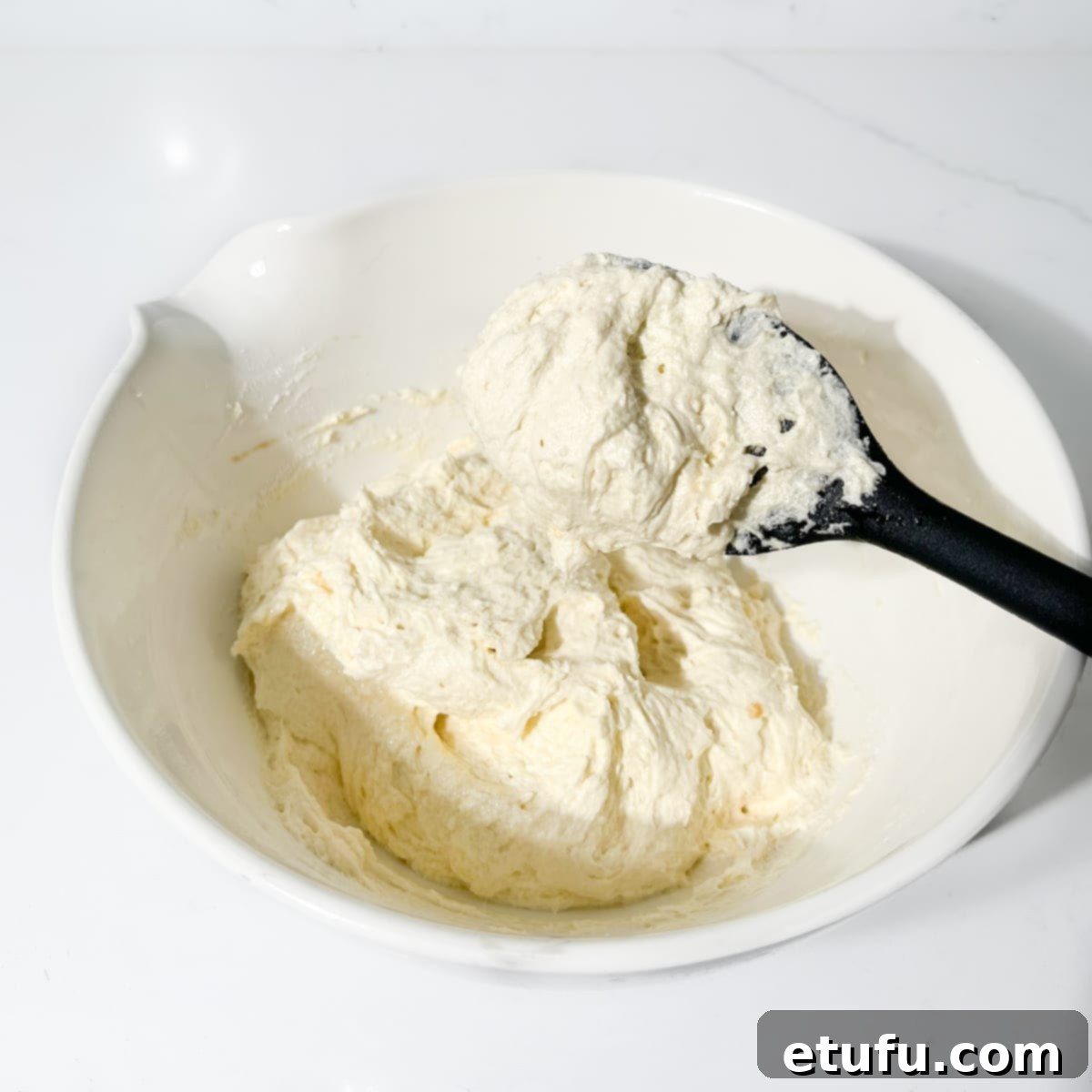 Eve's pudding batter ready for baking in a large white bowl.