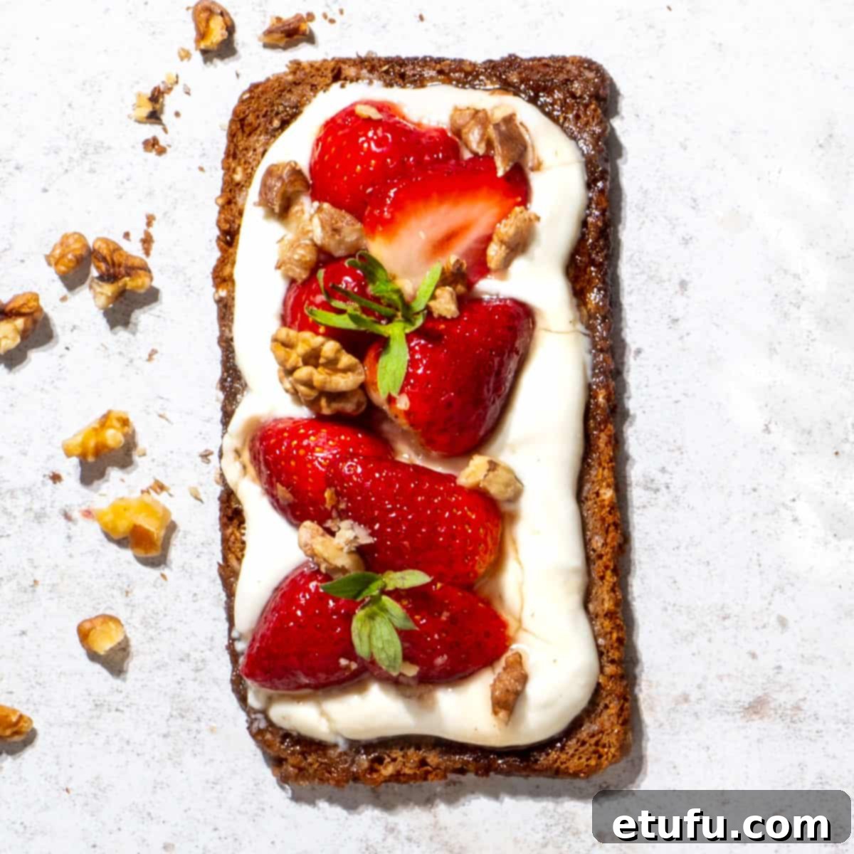Cottage cheese toast topped with sliced fresh strawberries, a drizzle of honey, and chopped nuts.