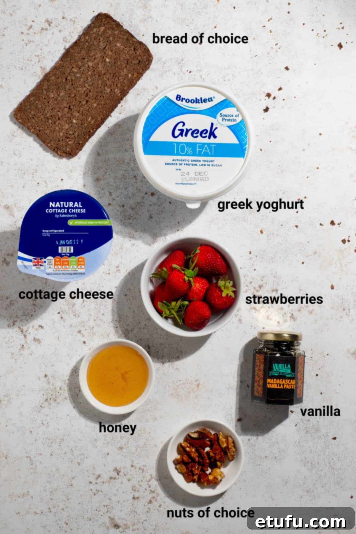 Ingredients for strawberry and honey cheesecake cottage cheese toast, including strawberries, honey, and a cottage cheese mix.