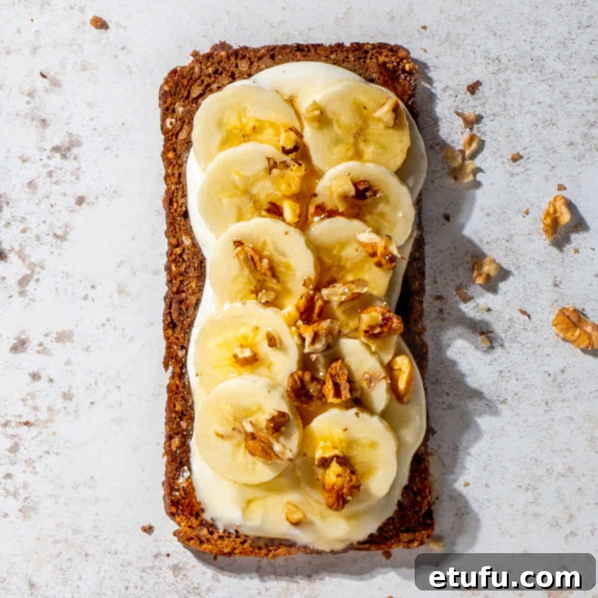 Cottage cheese toast topped with sliced bananas, a drizzle of honey, and scattered nuts.