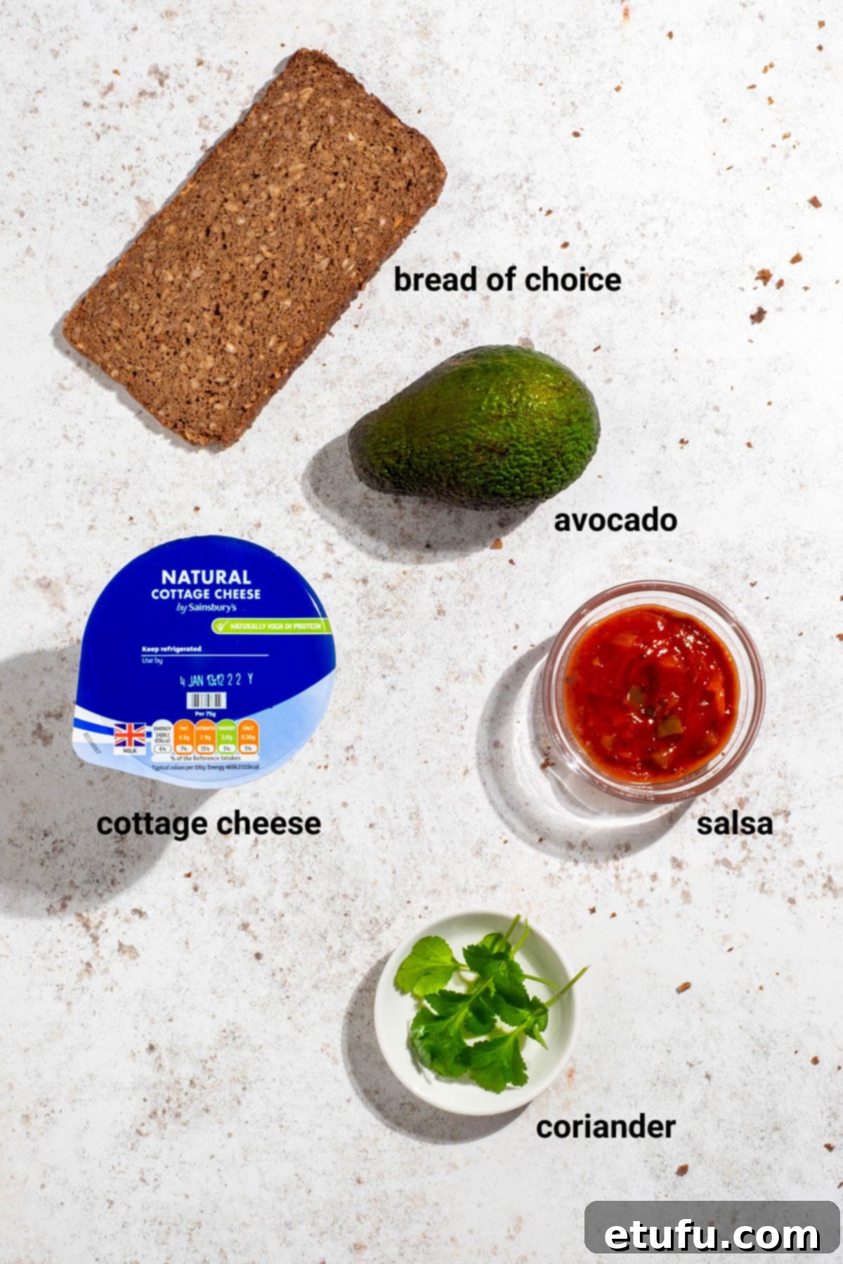 Ingredients laid out for avocado and salsa cottage cheese toast, including avocado, salsa, coriander, and bread.