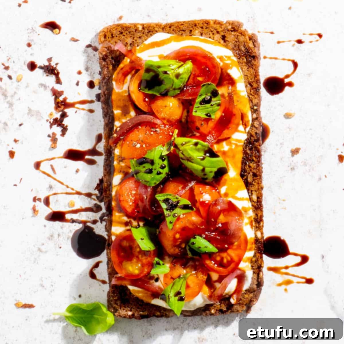 Cottage cheese toast adorned with fresh cherry tomatoes, basil leaves, and a drizzle of balsamic glaze.
