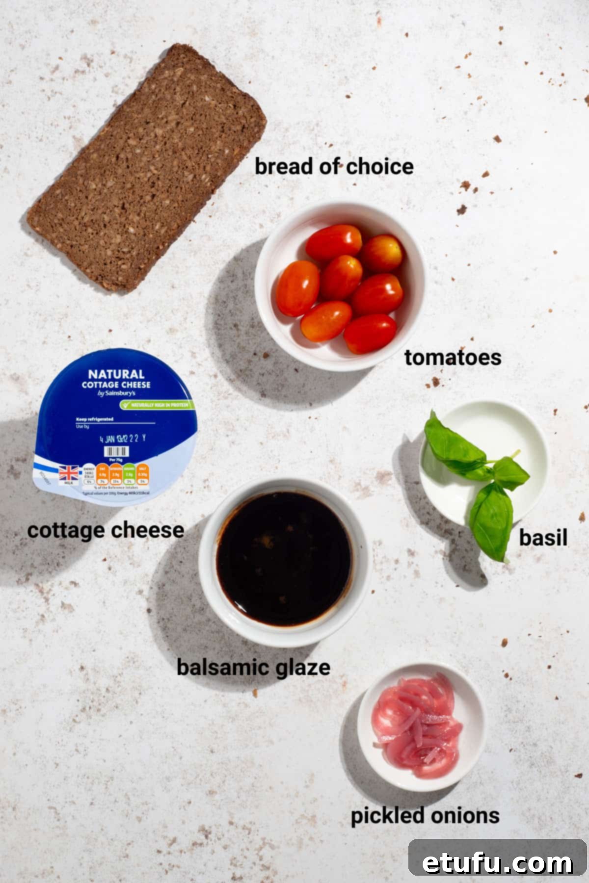 Ingredients for tomato and basil cottage cheese toast with balsamic glaze, including tomatoes, basil, and pickled onions.