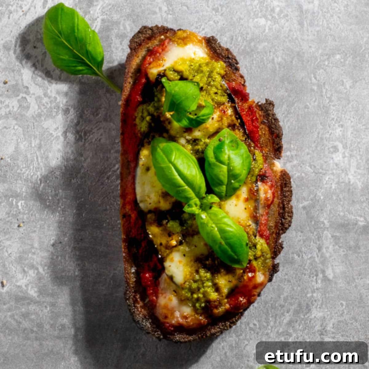 Aubergine/eggplant pizza toast on a grey background.