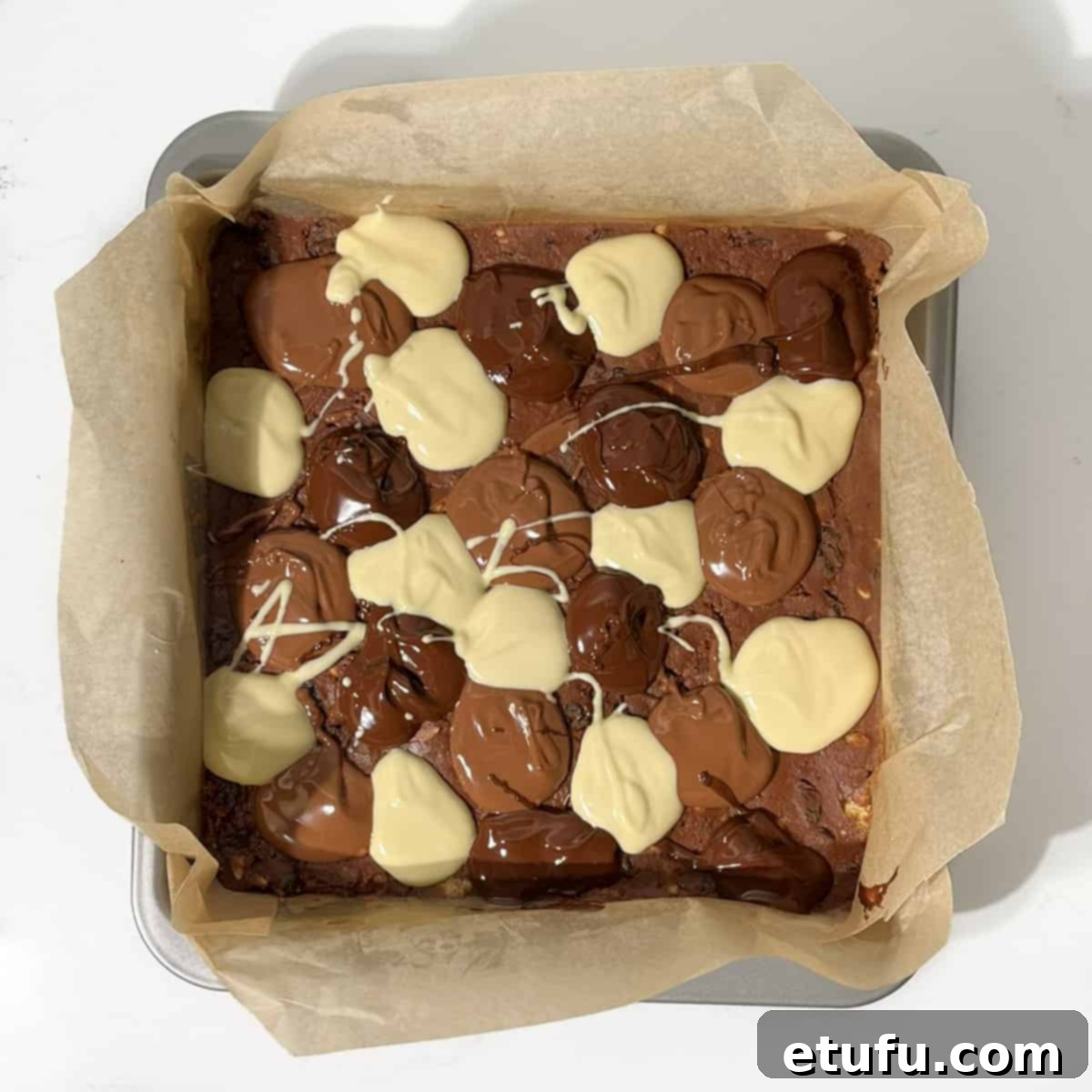 Spoonfuls of melted chocolate on the tiffin surface.