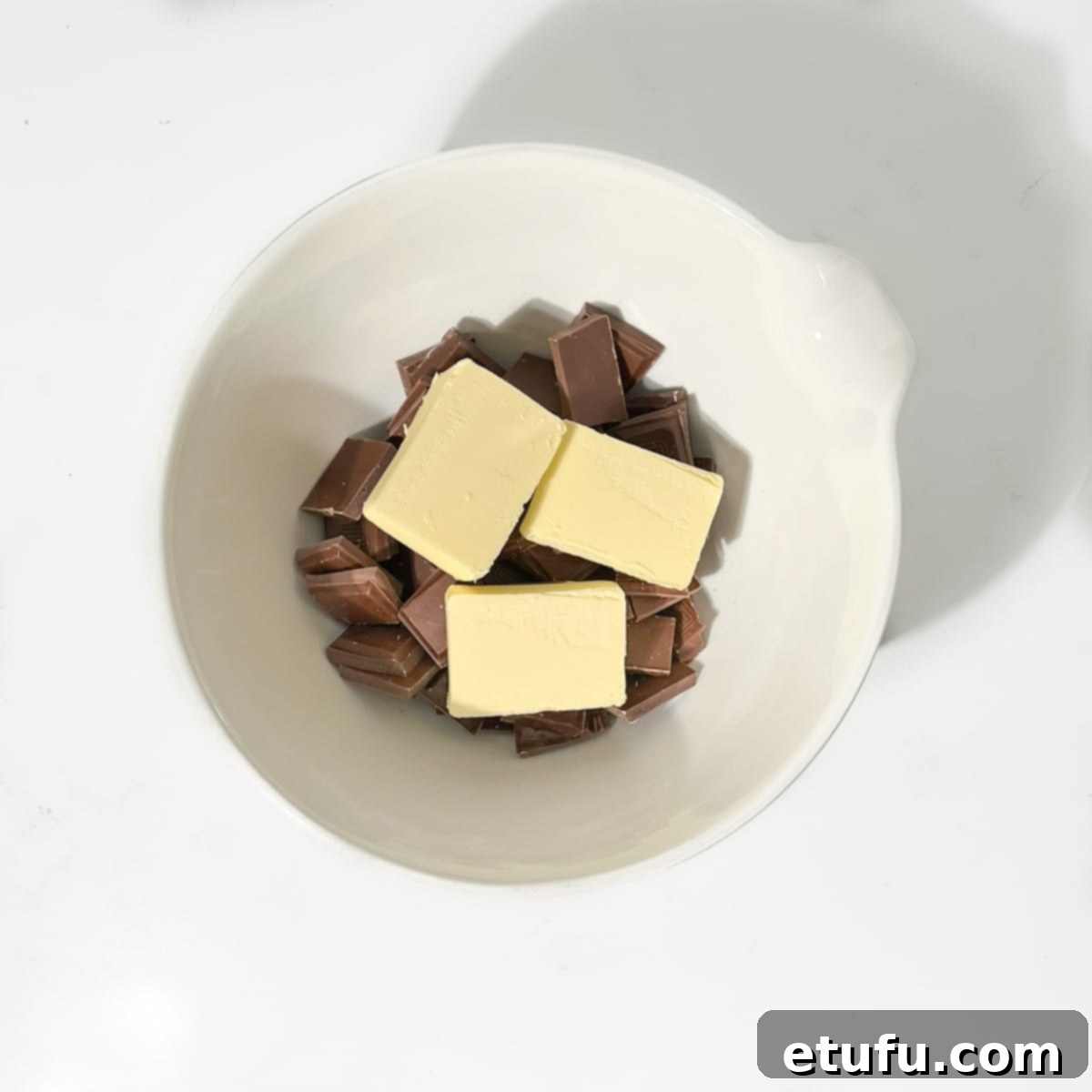 Chocolate and butter in a large white bowl.