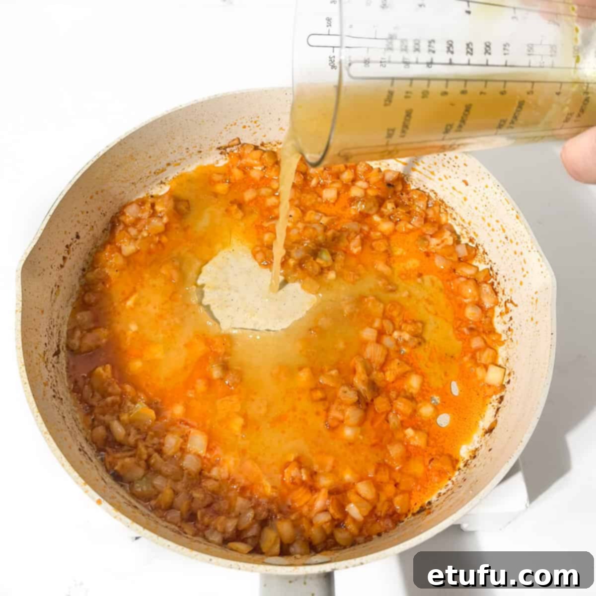 Exquisite Tuscan Marry Me Chicken Pasta 11 Pouring chicken stock into the pan with onions.