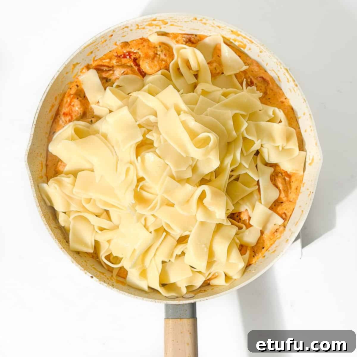 Exquisite Tuscan Marry Me Chicken Pasta 16 Adding the cooked pasta to the pasta sauce in a large pan.