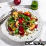 Nectarine salad on a large white plate, garnished with fresh basil leaves and crumbled cheese.