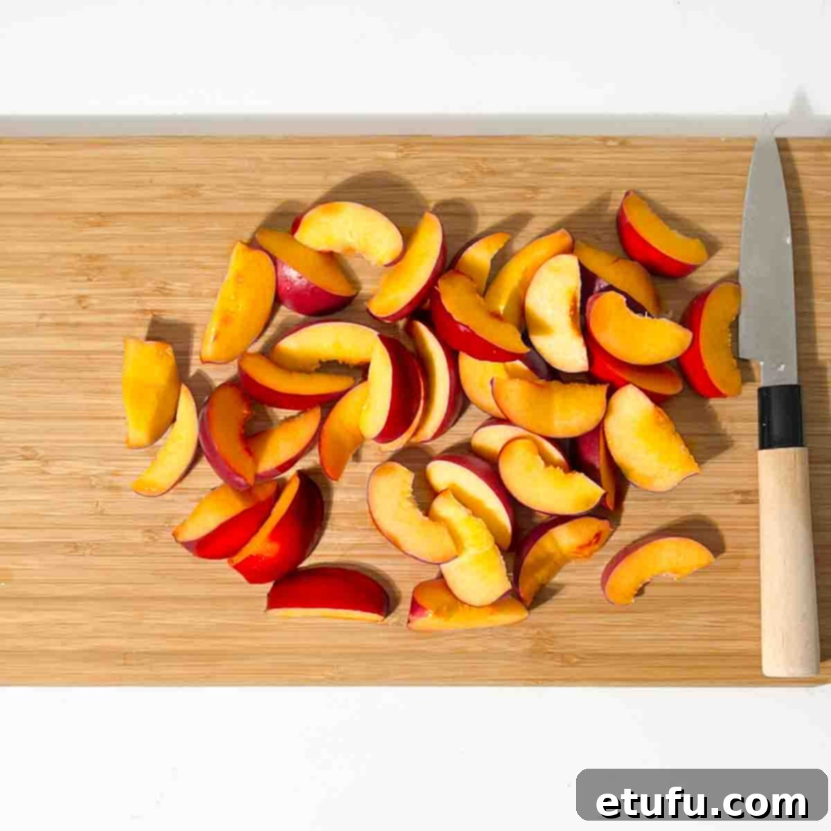 Perfectly sliced nectarines arranged on a rustic wooden chopping board, indicating preparation for the vibrant nectarine salad.