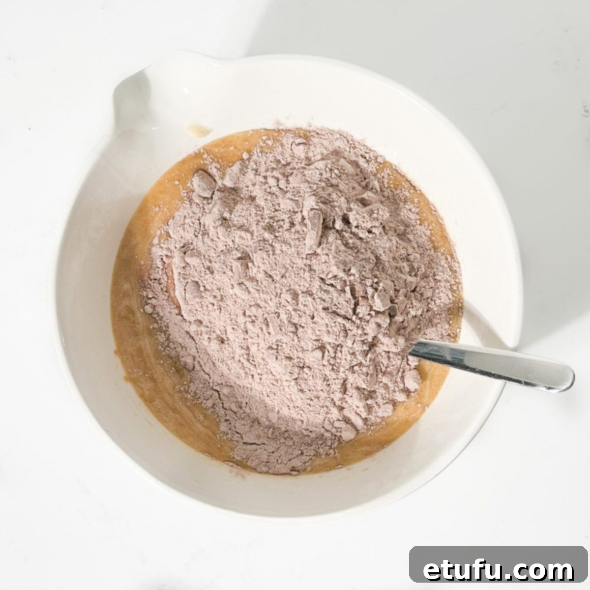 Golden Banana Chocolate Chunk Muffins 16 Adding the dry ingredients to the wet ingredients.