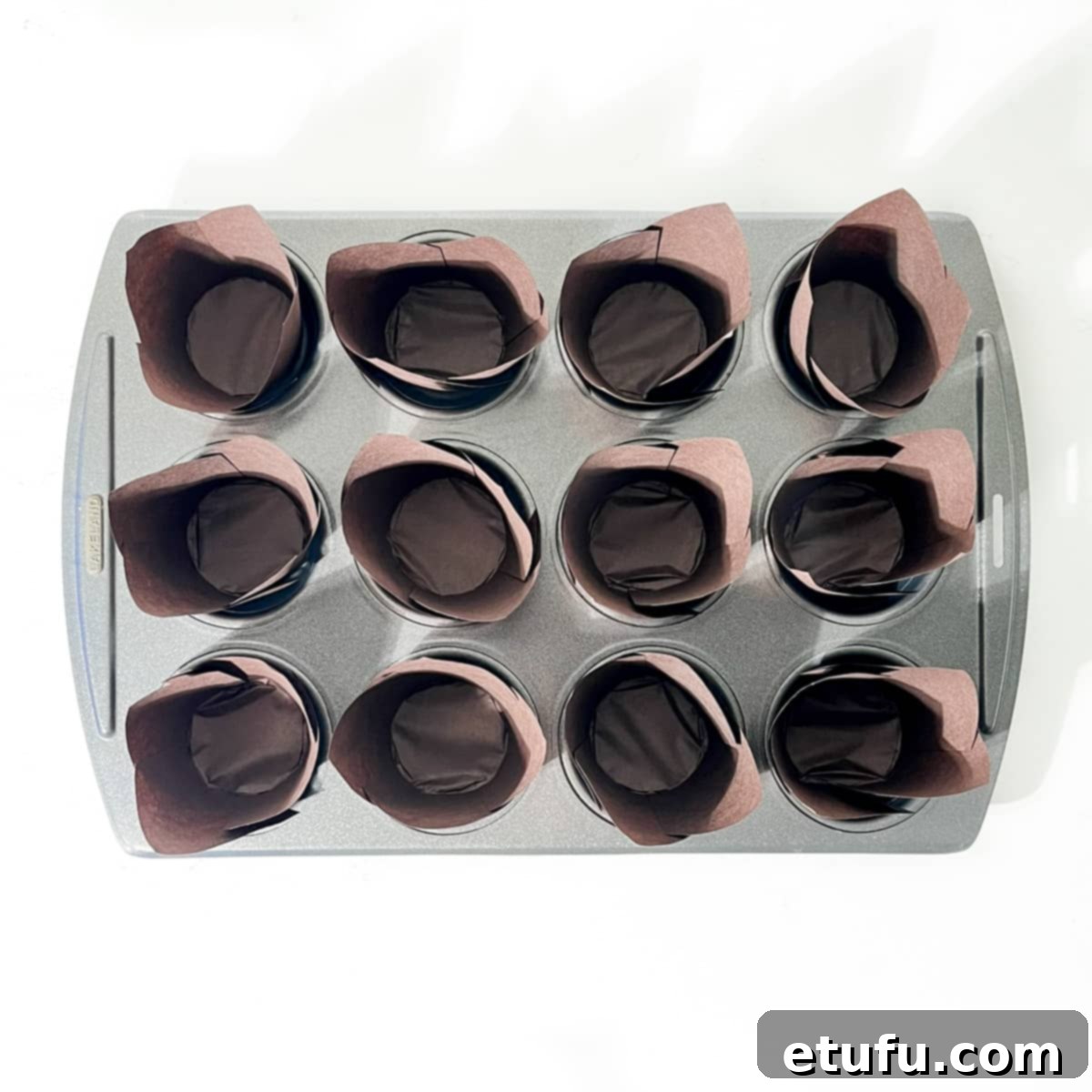 Golden Banana Chocolate Chunk Muffins 5 Lining a 12-hole muffin baking tin with paper liners.