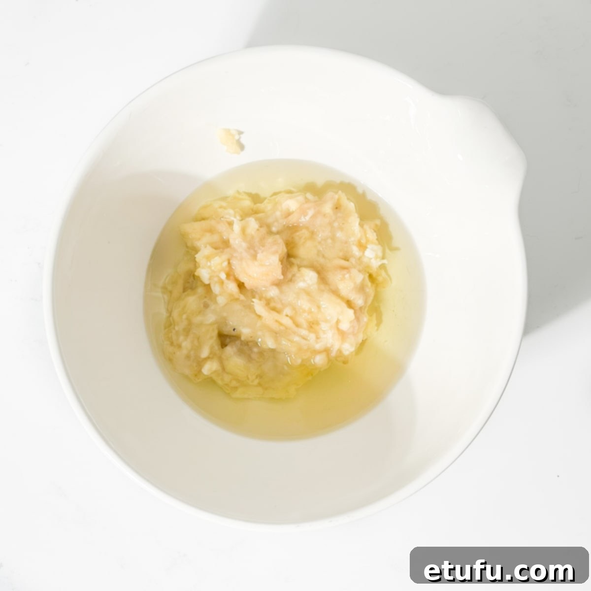 Golden Banana Chocolate Chunk Muffins 8 Adding oil to the mashed bananas.