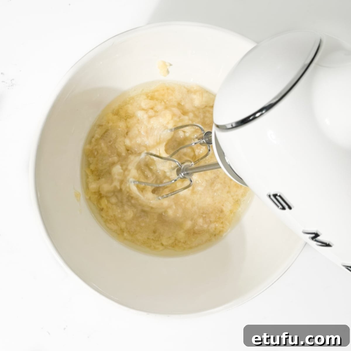 Golden Banana Chocolate Chunk Muffins 9 Beating the oil into the mashed banana with an electric hand mixer.