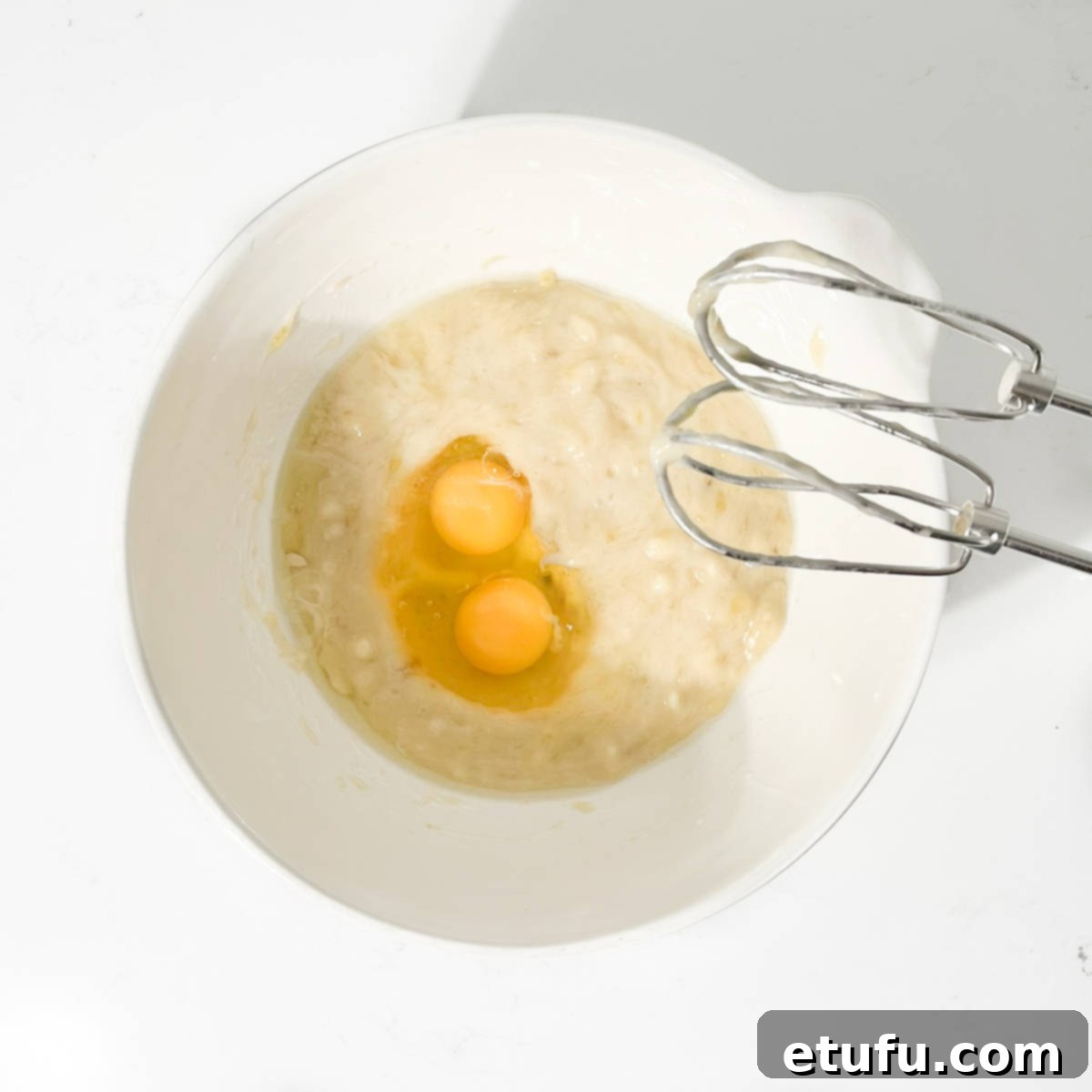 Golden Banana Chocolate Chunk Muffins 10 Adding the eggs to the mashed banana and oil.