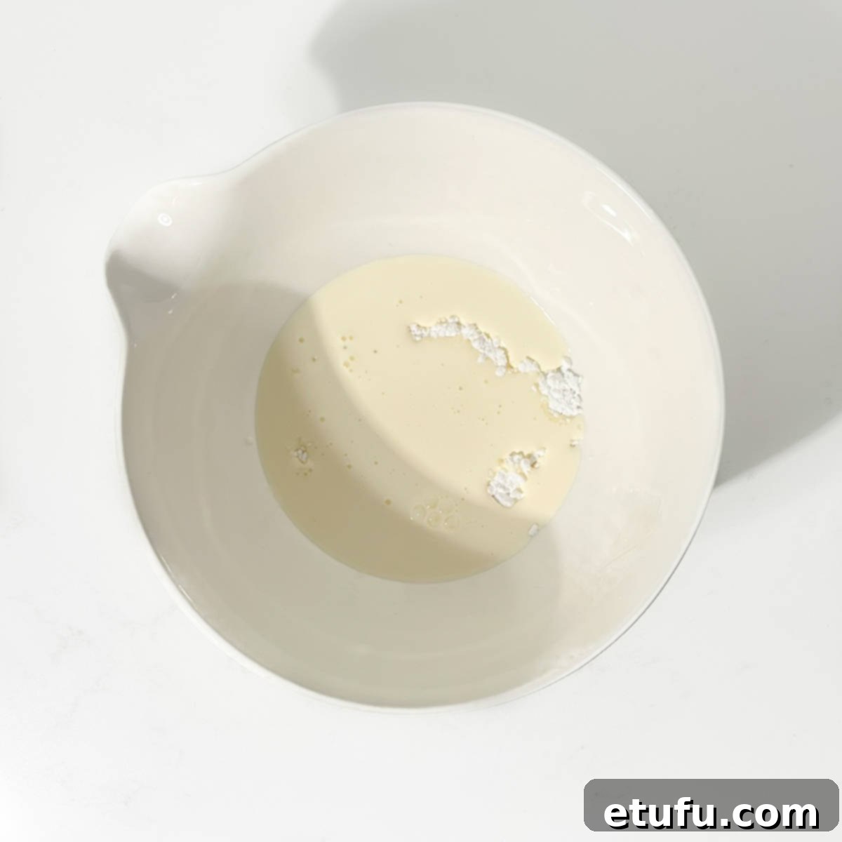 Double cream and icing sugar in a bowl for the strawberry croissants.