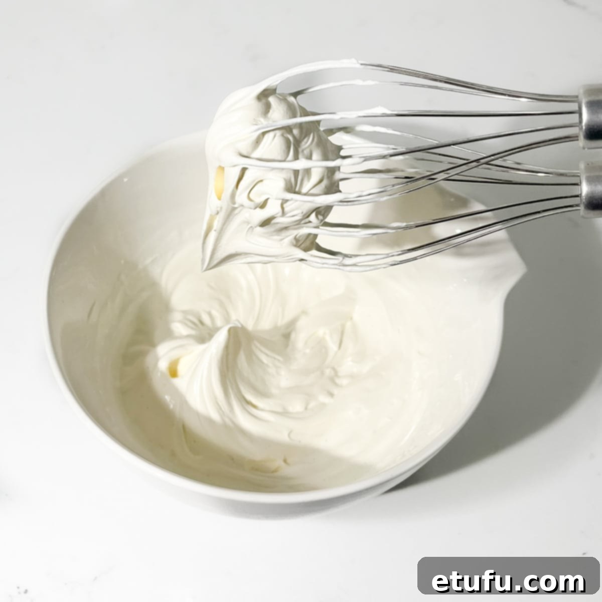 Whipping the mascarpone cream to soft peaks with an electric hand mixer.
