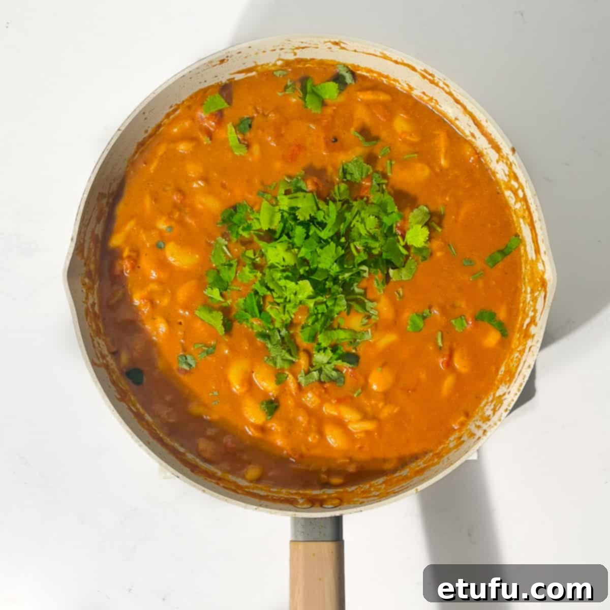 Adding coriander to the butter bean curry.