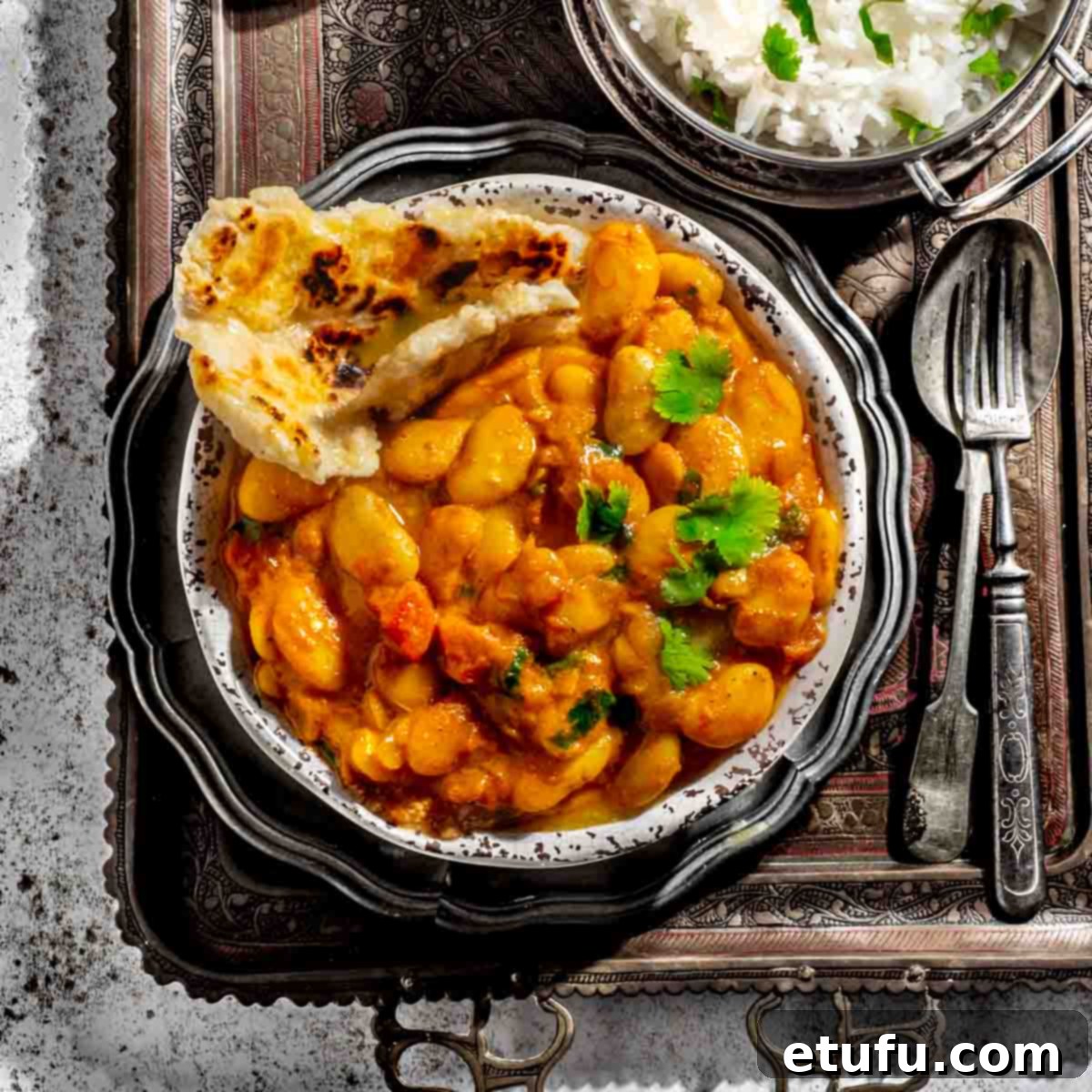 Butter bean curry in a bowl alongside a bowl of rice and a bowl of yoghurt.