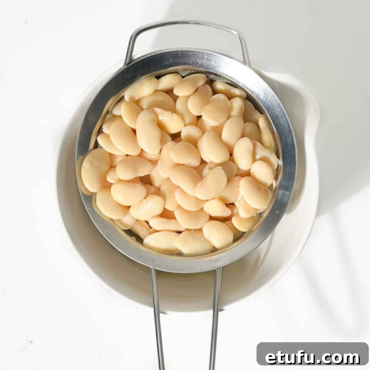 Draining the butter beans in a sieve for the butter bean curry.
