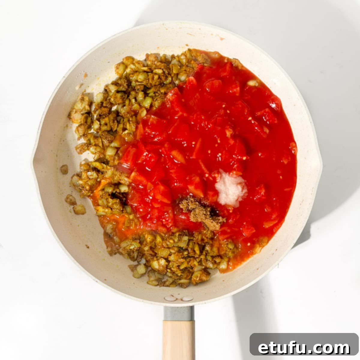 Adding the tinned tomatoes to the onions.