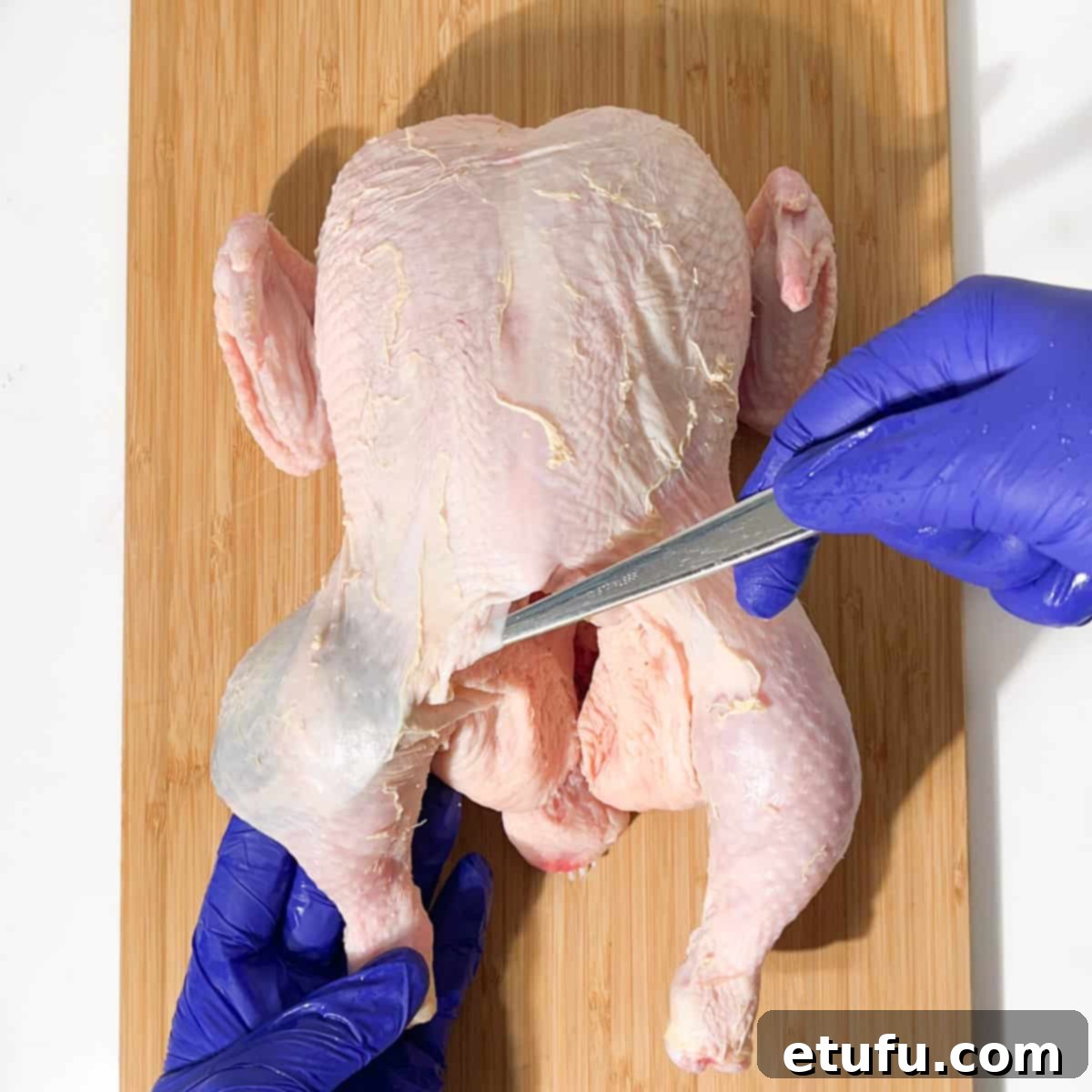 Loosening the chicken's leg skin with a spoon for the butter stuffing.