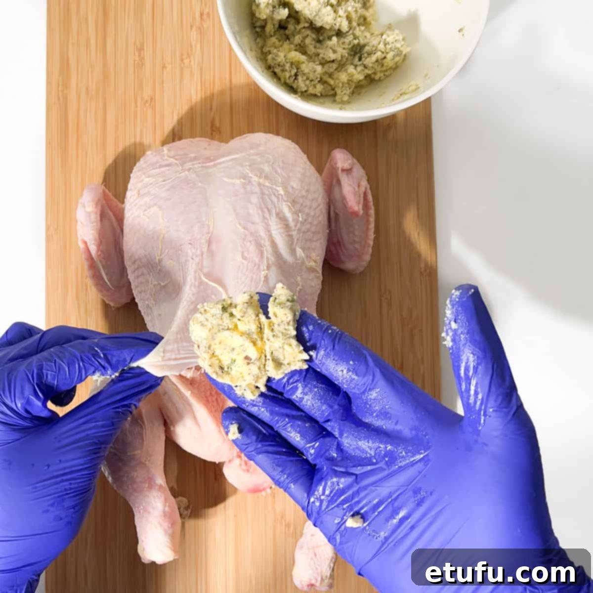 A pinched piece of compound butter held between fingers, ready for stuffing.