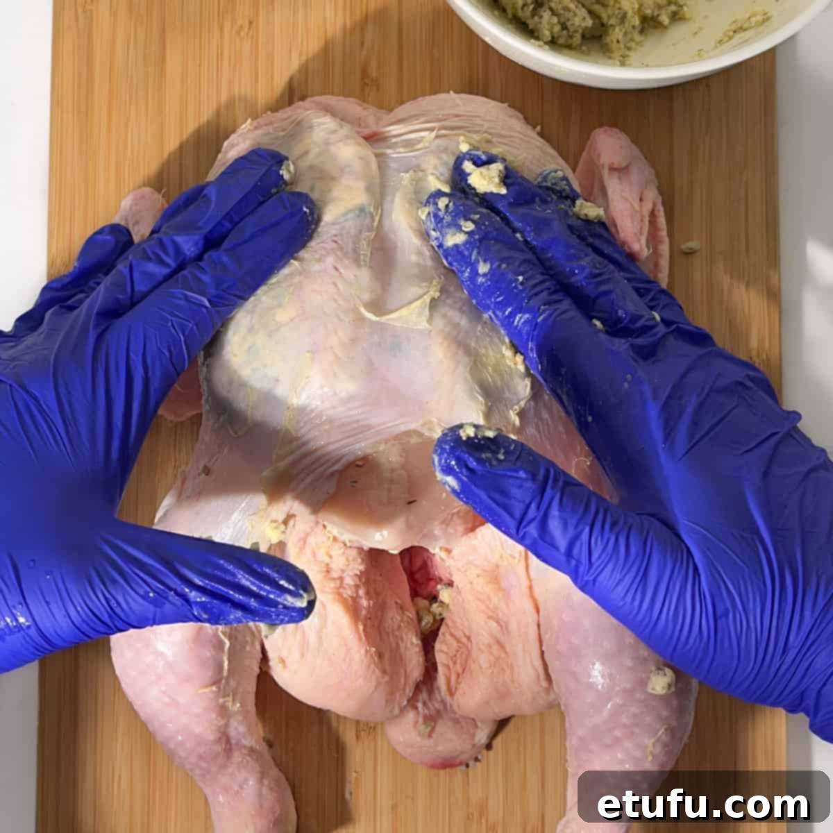 Spreading the compound butter evenly under the chicken skin by massaging from the outside.