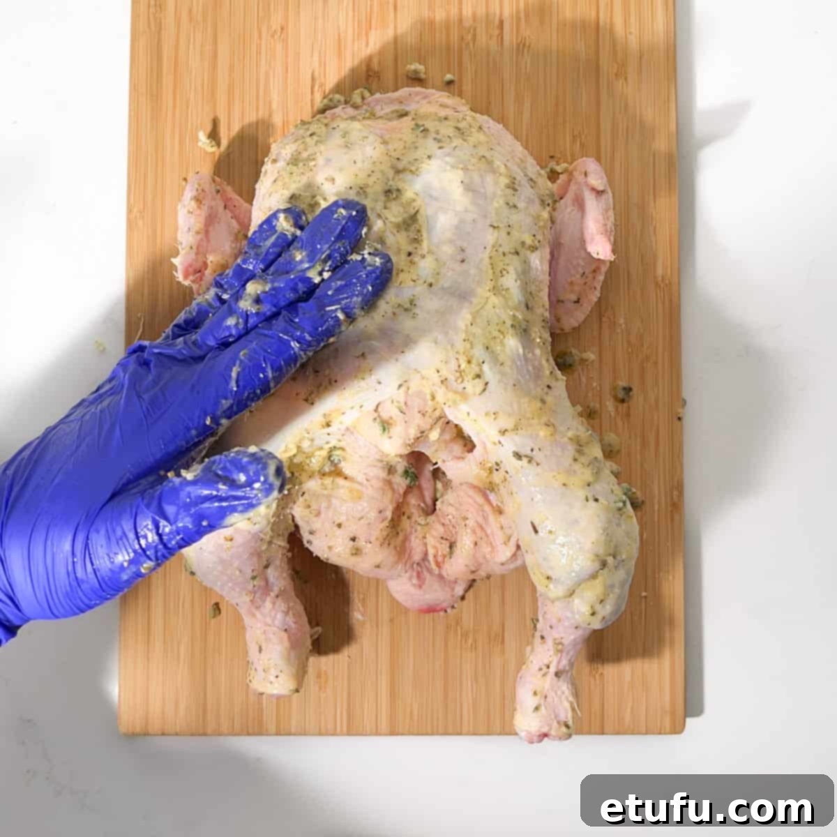 Rubbing butter all over the Greek roast chicken's exterior.