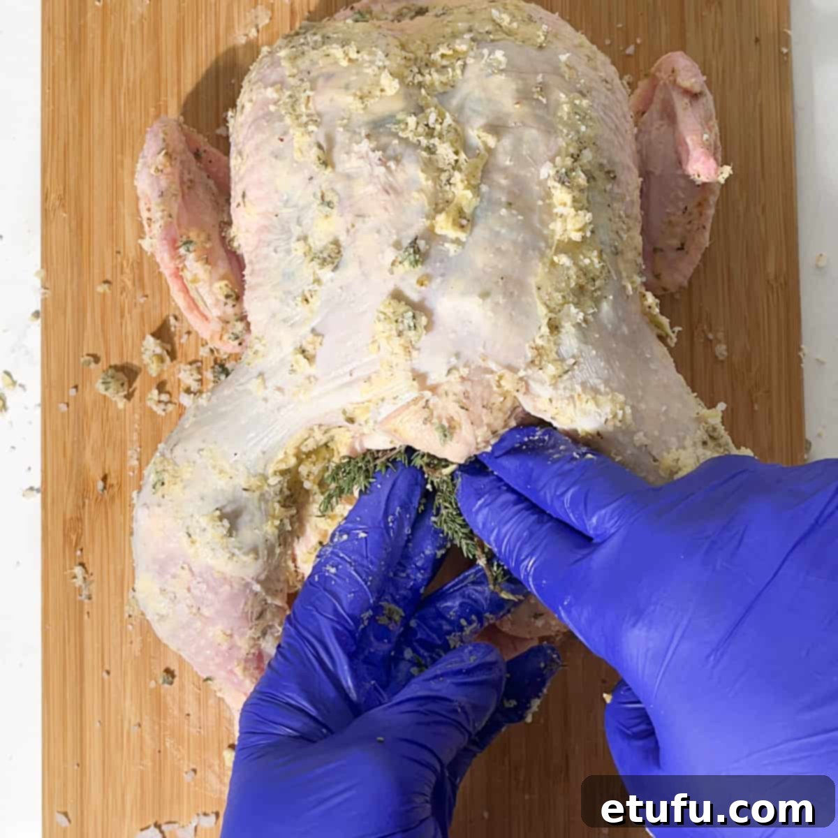 Stuffing thyme sprigs into the chicken cavity alongside the lemon.