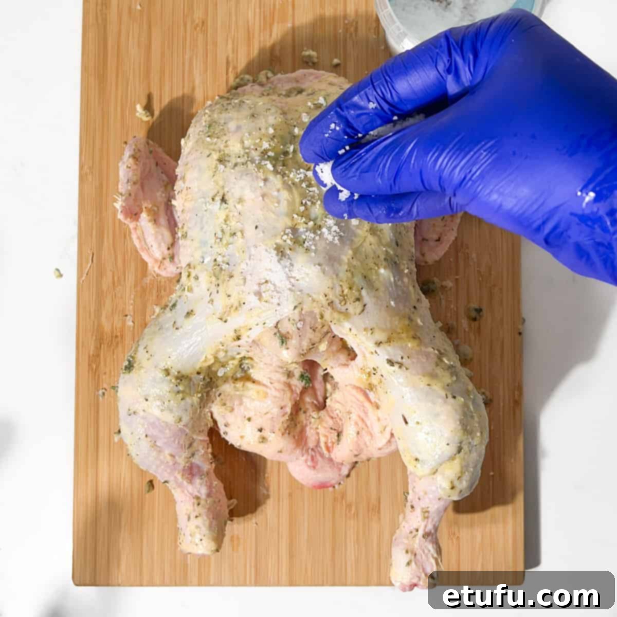 Sprinkling coarse sea salt generously over the Greek roast chicken.