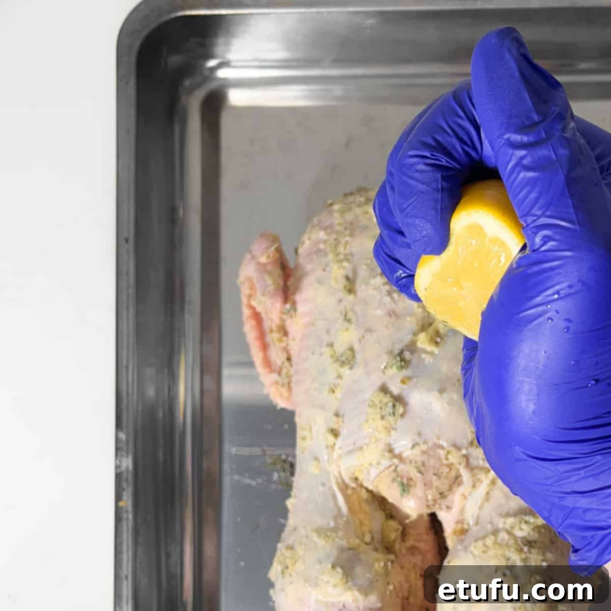 Squeezing fresh lemon juice over the seasoned Greek roast chicken.