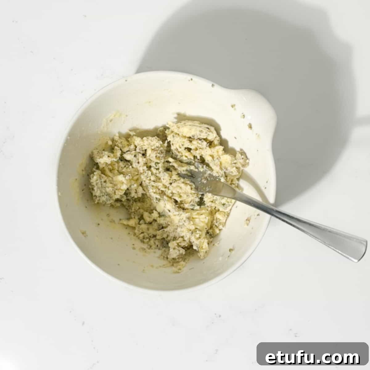 Compound butter for Greek roast chicken in a white bowl, thoroughly mixed.
