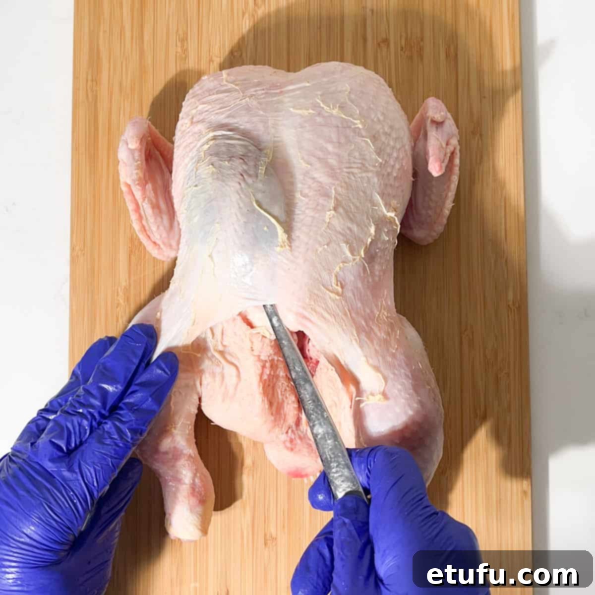 Loosening the chicken's breast skin with a spoon for the butter stuffing.