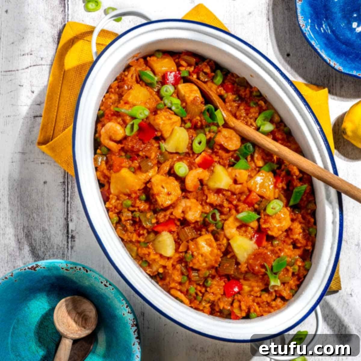 A beautifully presented chicken and chorizo jambalaya in a large, white oval pot, surrounded by colorful serving bowls.