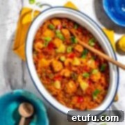 Chicken and chorizo jambalaya in a large, white oval pot surrounded by colourful bowls.