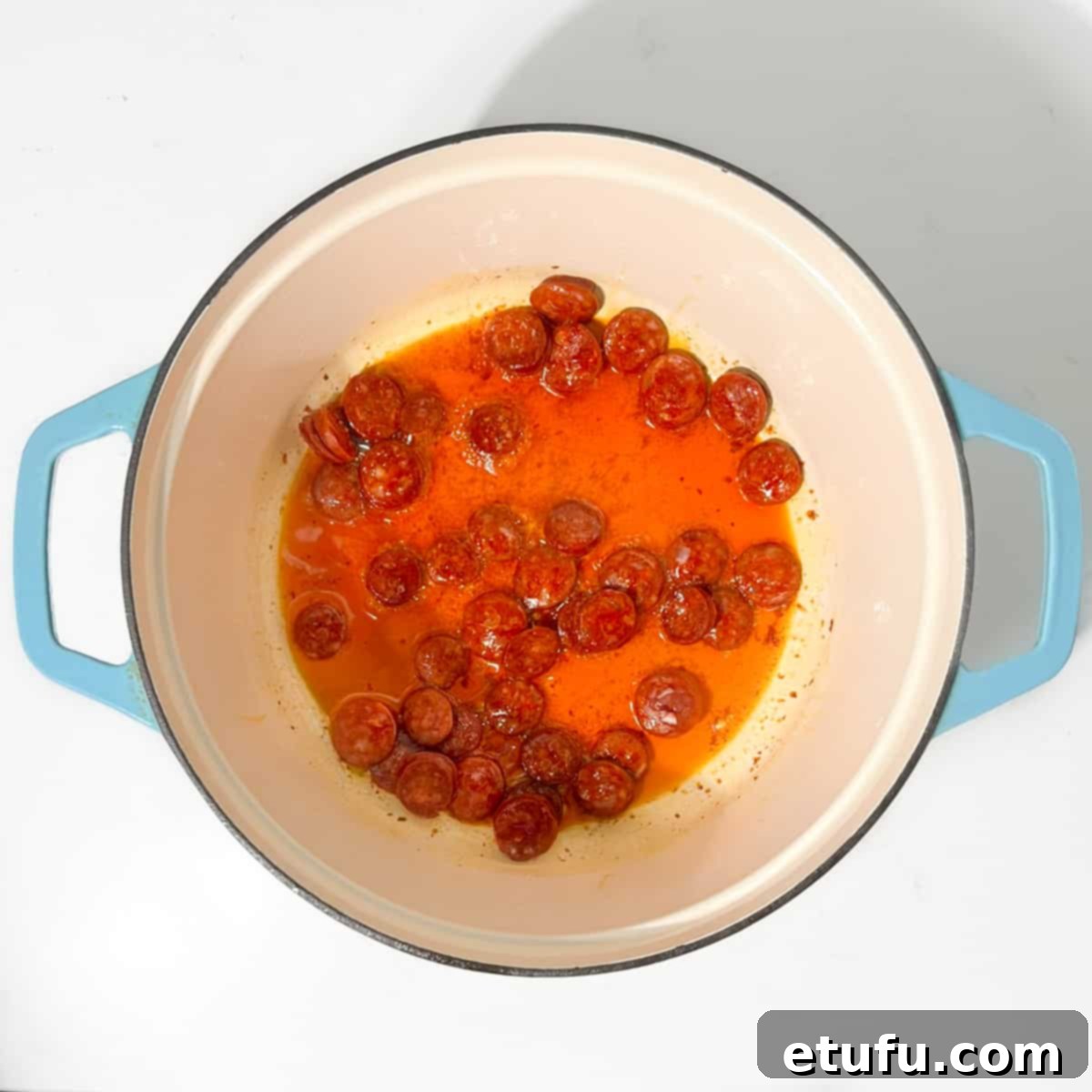 Frying the chorizo for the chicken and chorizo jambalaya in a large cast iron pot, releasing its flavorful oils.